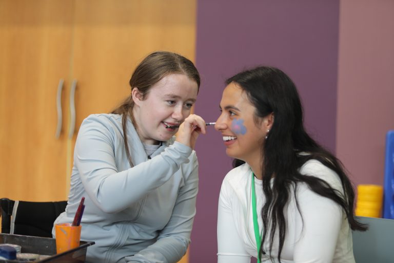 Two people enjoying a fun face painting session indoors